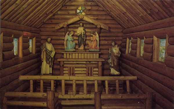 Text on back reads: "Lovely, rustic Chapel, dedicated to St. Jude, the Patron Saint of the Impossible. Hand-carved Altar and Communion Rail. Artistic hand-painted windows. Grotto shrine and Wonder Cave, Rudolph, Wisconsin." The interior of a log built Chapel, with statues beside and on the altar. The windows are painted.