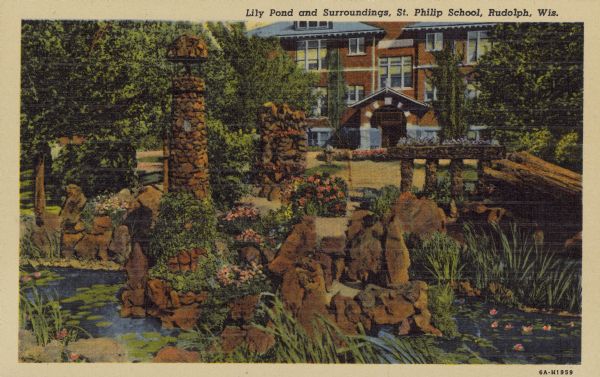 Text on front reads: "Lily Pond and Surroundings, St. Philip School, Rudolph, Wis." An elaborate structure of rocks surrounded by a lily pond. Through an opening in the trees, the St. Philip School can be seen. The brick school has an arched entrance and many windows.