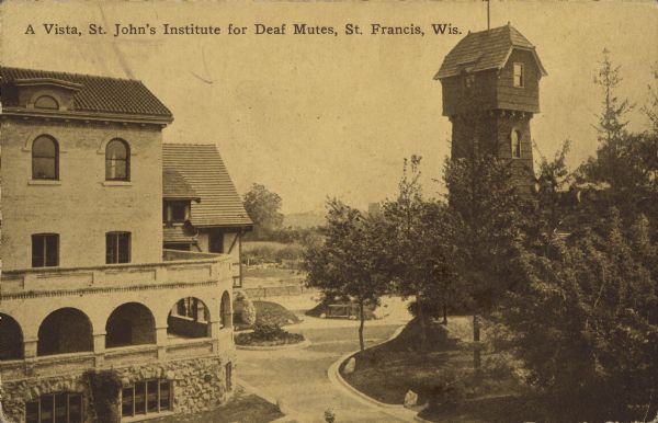 Text on front reads: "A vista, St. John's Institute for Deaf Mutes, St. Francis, Wis." An elevated view of the Institute grounds with buildings, streets and trees. A tower is on the right.