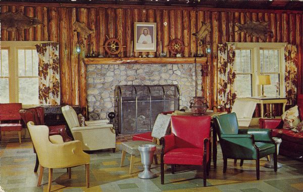 Text on reverse reads: "Interior of the Lodge &#8211; Moon Beach Camp. Rt. 1, St. Germain, Wisconsin." Comfortable chairs and a sofa are grouped in front of a fireplace. Wild animal skins decorate the half-log walls and the floor is linoleum.