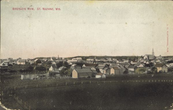 Text on front reads: "Birds Eye View, St. Nazianz, Wis." Elevated view of a small town from a field. A church is on the horizon.</p>