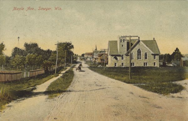Text on front reads: "Maple Ave., Sawyer, Wis." A view of an unpaved street with a church and other buildings on the right. On the left is a path, fence and trees with a windmill. Several horse drawn wagons are on the street.