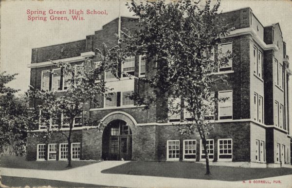 Text on front reads: "Spring Green High School, Spring Green, Wis." Three-story brick school building with an arched entrance. The grounds have sidewalks and trees.