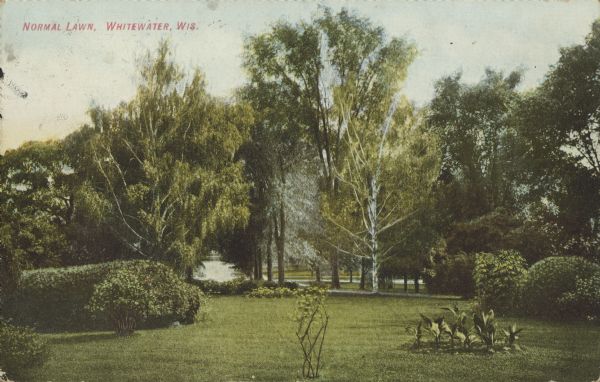 Text on front reads: "Normal Lawn, Whitewater, Wis." The lawn in front of the Whitewater Normal School. The area is landscaped with trees, shrubs and plants. The school graduated its first class of teachers in 1870.