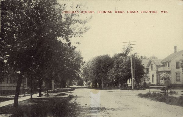Text on front reads: "Freeman Street, Looking North, Genoa Junction, Wis." Homes on an unpaved street in a tree-lined, residential neighborhood.