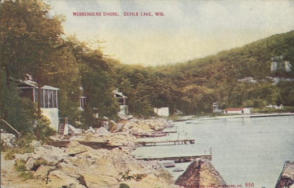 Text on front reads: "Messengers Shore, Devils [sic] Lake, Wis." Cottages and piers on the rocky shore of Devil's Lake. Tree-covered bluffs rise behind them.