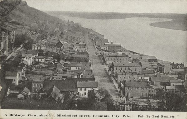 Caption reads: "A Birdseye View, showing Mississippi River, Fountain City, Wis." A town built between the bluffs and the Mississippi River. The unpaved main street can be seen running parallel to the shoreline.