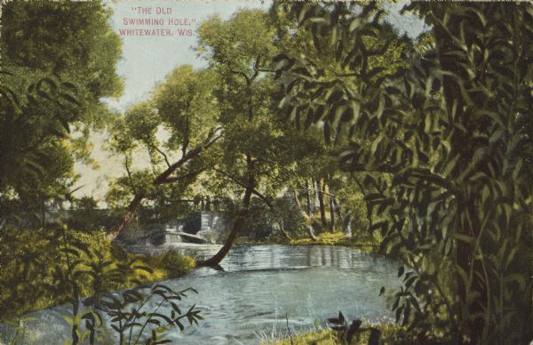 Text on front reads: "The Old Swimming Hole, Whitewater, Wis." A swimming area in a river, with a bridge in the background, surrounded by trees.