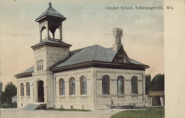 Text on front reads: "Graded School, Schleisingerville, Wis." A brick schoolhouse with arched windows and entrance, also a large belfry and ornate chimney. The name of the town was changed to Slinger in 1921.