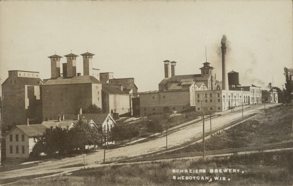 Text on front reads: "Schreiers Brewery, Sheboygan, Wis." The brewery was founded in 1856 by Konrad Schreier. A fire completely destroyed the original brewery in 1866 and the buildings seen in this image were built. In 1911 there was another fire and new concrete grain storage facilities were added. In 1997 the brewery was bought by Cargill and is in operation today.