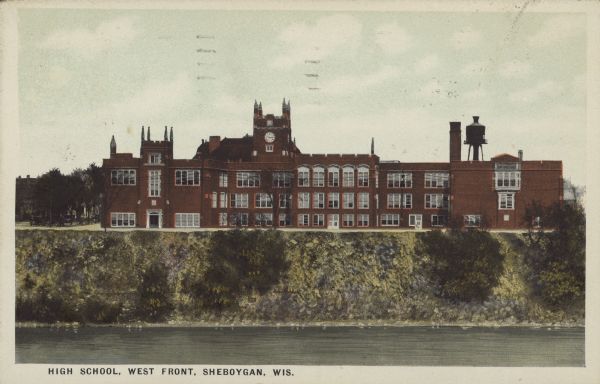 Text on front reads: "High School, West Front, Sheboygan, Wis." The school was named Sheboygan High School from 1922-1938, then Sheboygan Central High School 1939-1960. The Sheboygan River is in the foreground.
