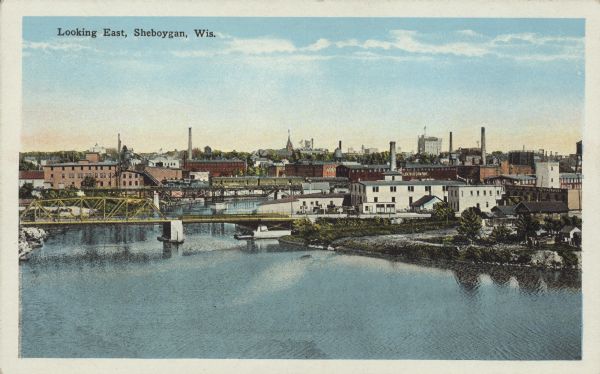 Text on front reads: "Looking East, Sheboygan, Wis." Elevated view of the city surrounding the Sheboygan River. There are many industrial buildings near the shoreline, and several bridges cross the river.