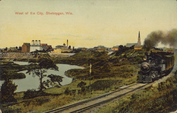 Text on front reads: "West of the City, Sheboygan, Wis." A view of the city looking towards the lake, with a locomotive on the right rounding the bend and traveling towards the camera. A river is below on the left and buildings are along the horizon.