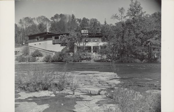 Text on reverse reads: "'Rock Ledge' Wisconsin's most picturesque gift shop located on the historical site at the Falls of the Sheboygan River, Sheboygan Falls." The dream of Helen Stroub, it was built on four different levels that followed the contours of the rock. The gift store was above and the apartment of Helen and Frank Stroub was below. Rock Ledge was dedicated on October 25, 1952. Originally the site of the old Rochester Co. sawmill and the Brickner Woolen Mills warehouse, it was empty for more than 50 years. ReMax/Universal Realty Company purchased it in 2021.
