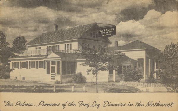 Text on front reads: "The Palms... Pioneers of the Frog Leg Dinners in the Midwest." On the reverse text reads: "Northeast of St. Paul. Frog Leg, Steak and Chicken Dinners." A two-story clapboard restaurant with sidewalks and trees on all sides. The sign reads: "The Palms, Fine Foods, Liquors."