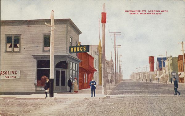 Text on front reads: "Milwaukee Ave. Looking West, South Milwaukee." View of an unpaved street lined with businesses. A man crosses the street and pedestrians are on the sidewalks. Signs read: "Drugs," "Gasoline for Sale" and "Pianos."