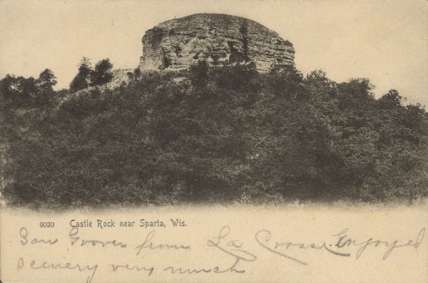 Text on front reads: "Castle Rock near Sparta, Wis." A formation about 600 feet high, having on its summit a large circular rock, named Castle Rock, for its resemblance to an ancient castle. The lower portion is covered with trees. It is northeast of the city and surrounded by more bluffs.