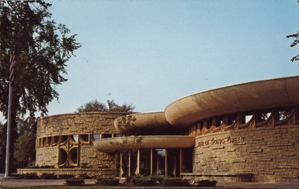 Text on reverse reads: "Bank of Spring Green. Spring Green, Wisconsin. Architecture by Taliesin Associated Architects of the Frank Lloyd Wright Foundation, William Wesley Peters, Chief Architect." From the Wisconsin Historical Society's Property Record: "Erected in 1972, the one-story building is composed of the flat-roofed, rock-faced stone-veneer bank with its plan of interesting circles, and a matching rock-faced stone wall that abuts the driveway. The bank features a ribbon of windows behind a concrete screen of geometric shapes, and curving canopies of smooth-faced concrete. Still in its historic use, the bank maintains excellent integrity."