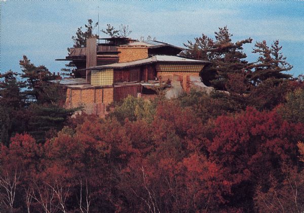 Text on the reverse reads: "The House on the Rock. Spring Green, Wisconsin 53588. The House on the Rock comes alive with spectacular autumn colors. This architectural marvel, built atop and into a 60 foot chimney rock, is the creation of Alex Jordan." A 14 room house built on a formation named Deer Shelter Rock during the 1940s. It was originally a weekend retreat, but grew to be much more.