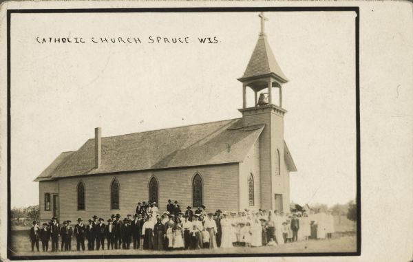 Group portrait of the congregation in front of the church. The church is clapboard with stained glass windows and a belfry. Caption reads: "Catholic Church, Spruce, Wis."