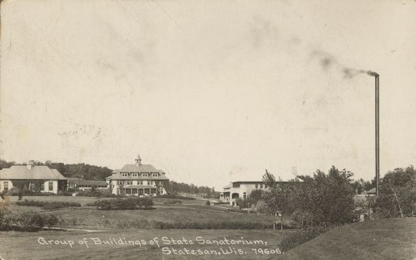 Text on front reads: "Group of Buildings of State Sanatorium, Statesan, Wis." A view of the Wisconsin State Tuberculosis Sanatorium, also known as “Statesan." The building in the center is the Administration Building. It was the only state run Sanatorium in Wisconsin. It opened on November 7, 1907 and closed in the fall of 1957. There is a tall smokestack on the right.