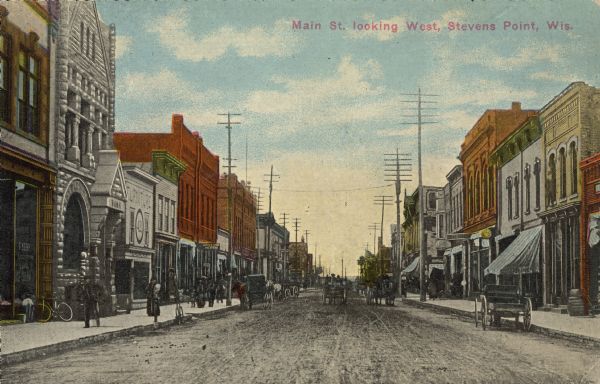 Text on front reads: "Main St. looking West, Stevens Point, Wis." A busy, unpaved street crowded with horse-drawn vehicles, bicycles and pedestrians on the sidewalk. Many businesses line the street including a Citizens National Bank, a furniture store, printer and the Ideal Theatre. 