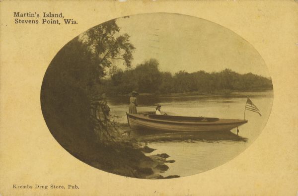 Text on front reads: "Martin's Island, Stevens Point, Wis." Two women, one standing and one sitting behind a boat pulled up on the shore of the Wisconsin River. There is an American flag on the prow. Trees are along the shoreline on the left and in the background.