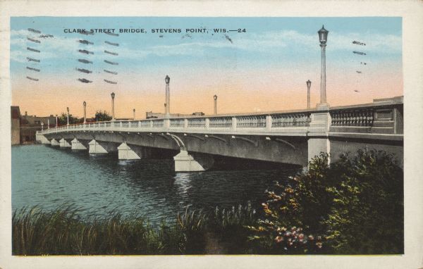 Text on front reads: "Clark Street Bridge, Stevens Point, Wis." View from shoreline towards a bridge built of stone, with lampposts, spanning the Wisconsin River.