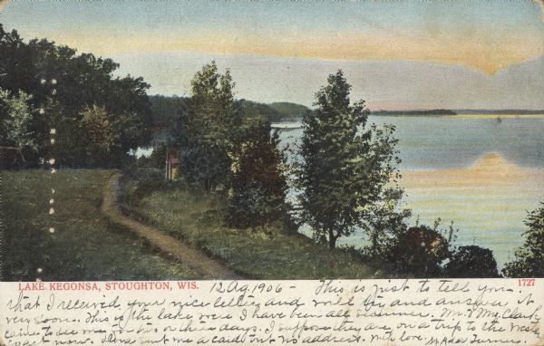 Text on front reads: "Lake Kegonsa, Stoughton, Wis." A path leads to a dwelling on the tree-lined shore above Lake Kegonsa. The sunset is reflecting on the lake on the right.