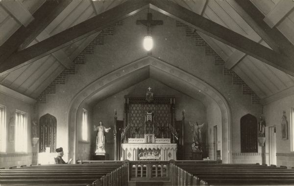 Handwritten on reverse: "Church of the Saints Maria-Anna." Interior of a church with an ornate altar and statues of Jesus and the Virgin Mary on the left and right. A member of the clergy is sitting in front of the pews on the left.