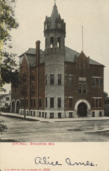 Text on front reads: "City Hall, Stoughton, Wis." Built in 1900 to house the city offices, library, police and fire departments with a 701 seat opera house on the upper floors. The building is brick, built in the Romanesque Revival style. The Stoughton Opera House has been restored and now plays host to a wide variety of musical and theatrical performances.