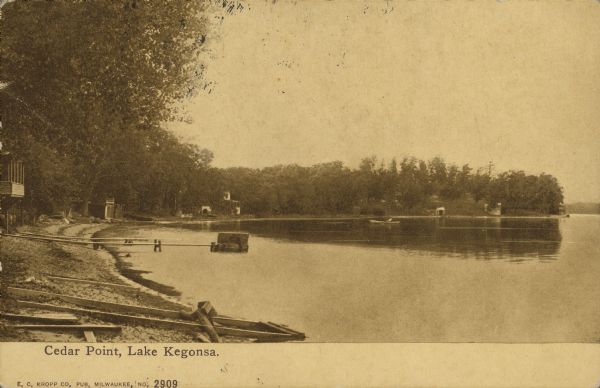 Text on front reads: "Cedar Point, Lake Kegonsa." Cottages, docks and trees on the shore of a bay, with the shoreline curving to the right and a point of land jutting out into Lake Kegonsa. One rowboat is on the water.