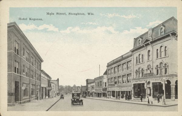 Text on front reads: "Hotel Kegonsa. Main Street, Stoughton, Wis." View down a street lined with businesses. Automobiles are on the street and pedestrians are on the sidewalks. On the left is the Hotel Kegonsa. The building on the right has a sign that reads "Beavers." This is the headquarters for the fraternal organization "Beavers Reserve Fund Fraternity" founded in 1902.