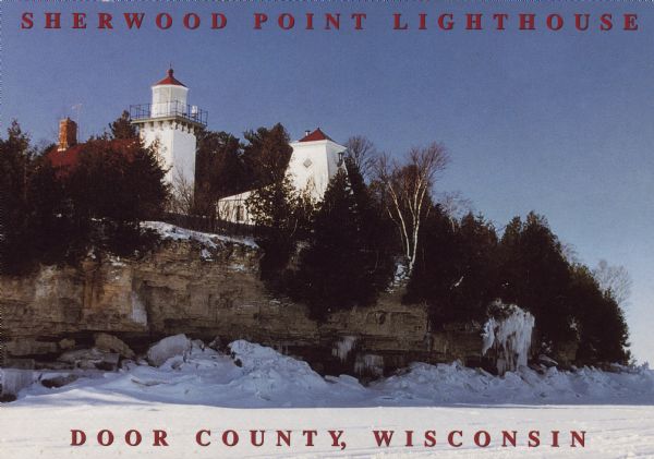 Text on front reads: "Sherwood Point Lighthouse, Door County, Wisconsin." On reverse: "Sherwood Point Lighthouse is near Potawatomi State Park, north of Sturgeon Bay on Green Bay in Door County, Wisconsin." The lighthouse was built of red brick, began operation in 1883 and had the distinction of being the first manned light on the Great Lakes. It was automated in 1983.