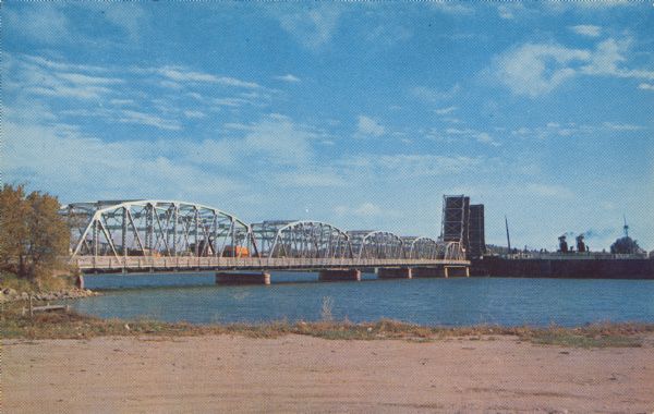 Text on reverse reads: "Sturgeon Bay Drawbridge Spanning, Sturgeon Bay Canal, Sturgeon Bay, Wis." Traffic is backed up as a ship passes through the span of a double-bascule bridge over the canal.