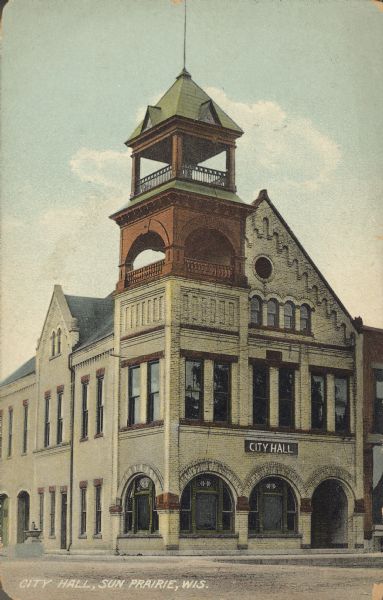 Text on front reads: "City Hall, Sun Prairie, Wis." The Romanesque Revival City Hall was built of brick in 1895. The building has decorative elements, a bell tower and arched windows and doors.