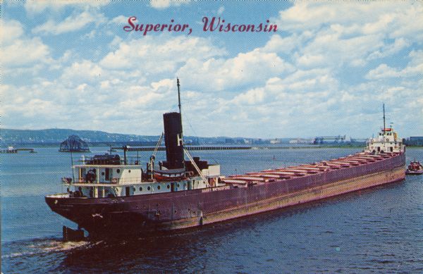 Text on front reads: "Superior, Wisconsin." On reverse: "Harry Wm. Hosford. This view was taken from the Arrowhead Bridge. It just unloaded its cargo of coal and will take on a load of ore and proceed to the steel mills in the lower lakes. Length - 512.9 ft. Capacity - 9,000 tons." The ship was launched as <i>F.B. Squire</i> and renamed in 1936. The harbor, city and hills are in the background.