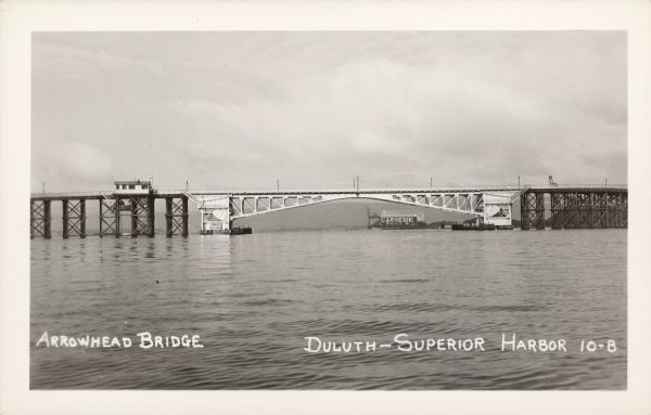 Text on front reads: "Arrowhead Bridge, Duluth-Superior Harbor. The bridge connected Superior, Wisconsin, with Duluth, Minnesota, over the St. Louis River. Built in 1927, it was mostly a wooden trestle with a steel draw span to allow ships to pass through. The bridge was demolished in 1985. Signs read: "Danger" and "Carnegie Dock 2."
