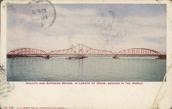 Text on front reads: "Duluth and Superior Bridge, in Length of Draw, Second in the World." Also called the Interstate Bridge, it was opened in July 1897. A toll bridge made up of long wooden trestles on each end, a 485 foot steel truss swing span was between two 325 foot steel humpback trusses. After the new "High Bridge" was opened in 1961, traffic dwindled and the swing span was locked open. It was mostly removed in the 1970s.