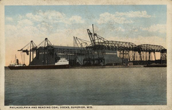 Text on front reads: "Philadelphia and Reading Coal Docks, Superior, Wis." View across the water towards a cargo ship docked for loading or unloading. 