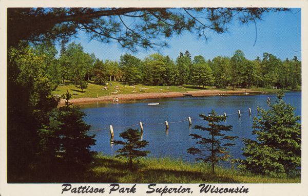 Text on front reads: "Pattison Park, Superior, Wisconsin." On reverse: "Pattison State Park. 12 Miles from Superior, Wisc. on Hiway 35. Interfalls Lake is a delightful lake formed by the damming of the Black River. Sand Beach – Swimming Area – Picnic and Camping Grounds in a beautiful setting of Norway Pine. River Gorges, Cascades and Waterfalls are attractions at Pattison State Park." A bathing beach with swimmers in the water and sun bathers on the sand. A safety rope outlines the swimming area. The beach is surrounded by trees.
