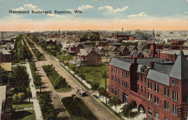 Text on front reads: "Hammond Boulevard, Superior, Wis." A bird's-eye view of a tree and home lined boulevard in a neighborhood. A horse-drawn wagon is on the right side of the street. The buildings of the city can be seen in the distance.