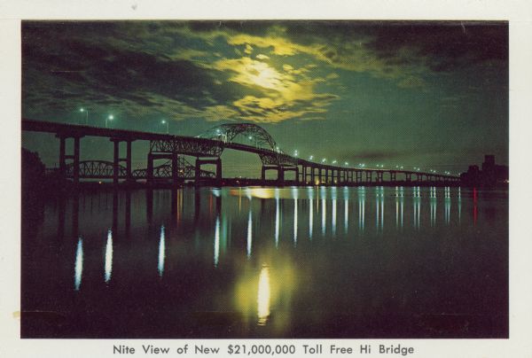 Cover title of souvenir folder reads: "Souvenir folder of Superior, Wisconsin 17 Natural Color Views. Caption for this image reads: "Nite View of New $21,000,000 Toll Free Hi Bridge". Text inside front cover: "America's Most Westerly Inland port located at the head of Lake Superior. Superior has the Largest Ore Docks in the World — Tallest Grain Elevators — Largest Dry Docks on the Great Lakes — Beautiful Parks — 18 Hold Golf Course — Barker's Island Free Marina where tourists may park or launch their boats to enjoy a panorama view of the harbor — Hay Fever Haven — Gateway to Lake Superior Circle Route."