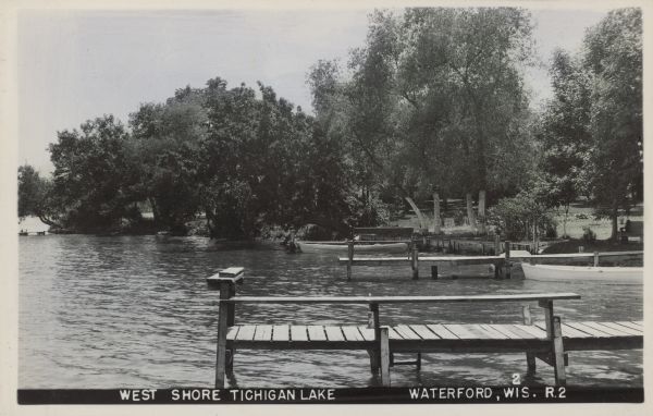 Text on front reads: "West Shore Tichigan Lake, Waterford, Wis." Docks and boats on a wooded shoreline. Tichigan Lake is on the Fox River, and there is a dam at Waterford.