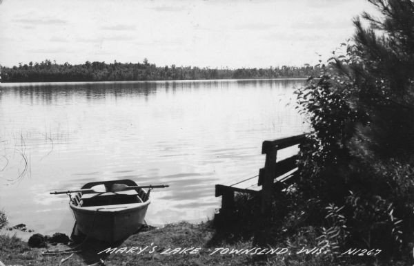 Text on front reads: "Mary's Lake, Townsend. Wis." A rowboat and bench on the shore of a lake, and trees along the far shoreline. Mary's Lake is southwest of Townsend.