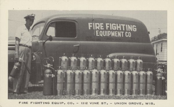 Text on front reads: "Fire Fighting Equip. Co. - 1312 Vine St. - Union Grove, Wis." On reverse: "R.K. Brown's Fire Fighting Equip. Co. Now offers you these added new features. Fast country wide service. Our trucks are now equipped with special designed equipment to fill and service all types and makes of fire extinguishers, at your place of business. Yes, Carbon Dioxide extinguishers included. Complete line of Kiddie fire extinguishers. Oxygen masks and breathing equipment by Cycle-Flo. May We Be Of Service To You? Fire Fighting Equip. Co. 1312 Vine St. Union Grove, Wis. - Ph. 216. Racine - Ph. Enterprise 6050." A man stands with a fire extinguisher in front of a van with a display of 24 more fire extinguishers. "Fire Fighting Equipment Co." is painted on the van. 