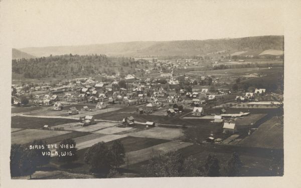 Text on front reads: "Bird's Eye View, Viola, Wis." Aerial view of the town with farms in the foreground and wooded hills on the horizon.