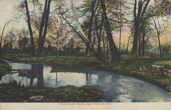 Text on front reads: "Weyerhorst Creek, near Oshkosh, Wis." A rowboat is moored at the shore of a creek. The background is filled with trees.