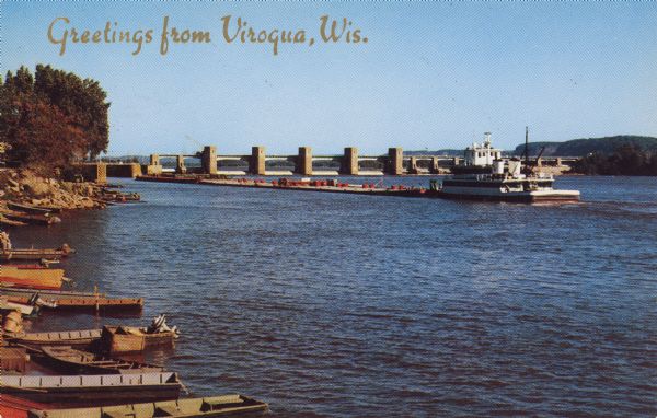 Text on front reads: "Greetings from Viroqua, Wis." On reverse: "U.S. Government Dam on the Mississippi River." A cargo barge is about to pass through locks on the Mississippi River. Boats and pier can be seen on the left. The U.S. Lock & Dam #8 is actually located at Genoa, Wisconsin.