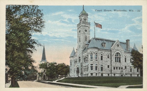 Text on front reads: "Court House, Waukesha, Wis." Built in 1893 of limestone in the Richardson Romanesque style, it is now the home of the Waukesha County Historical Society and Museum. In the background on the left is St. Joseph's Catholic Church.